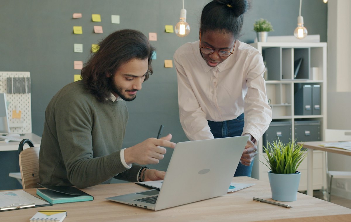 Two colleagues reviewing a plan on a laptop